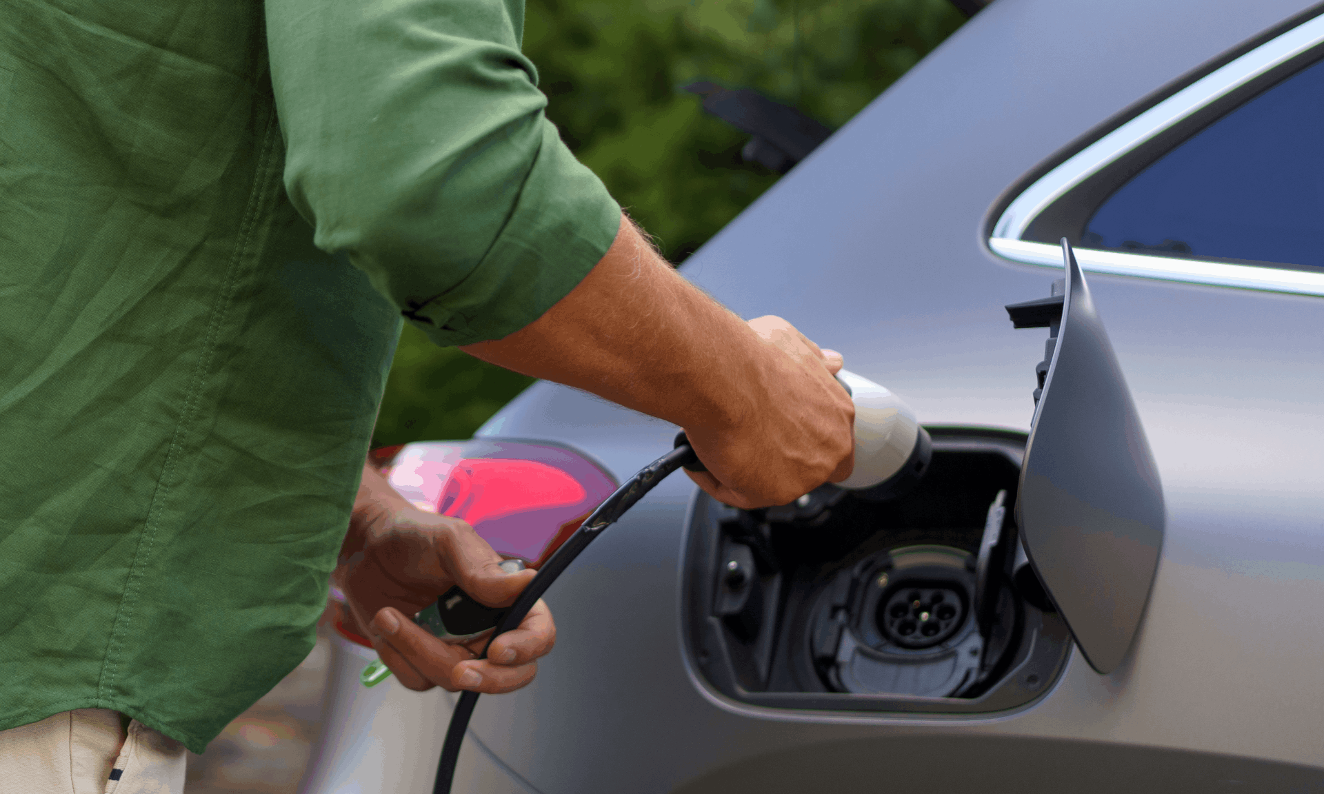 man in green shit plugging car in to charge