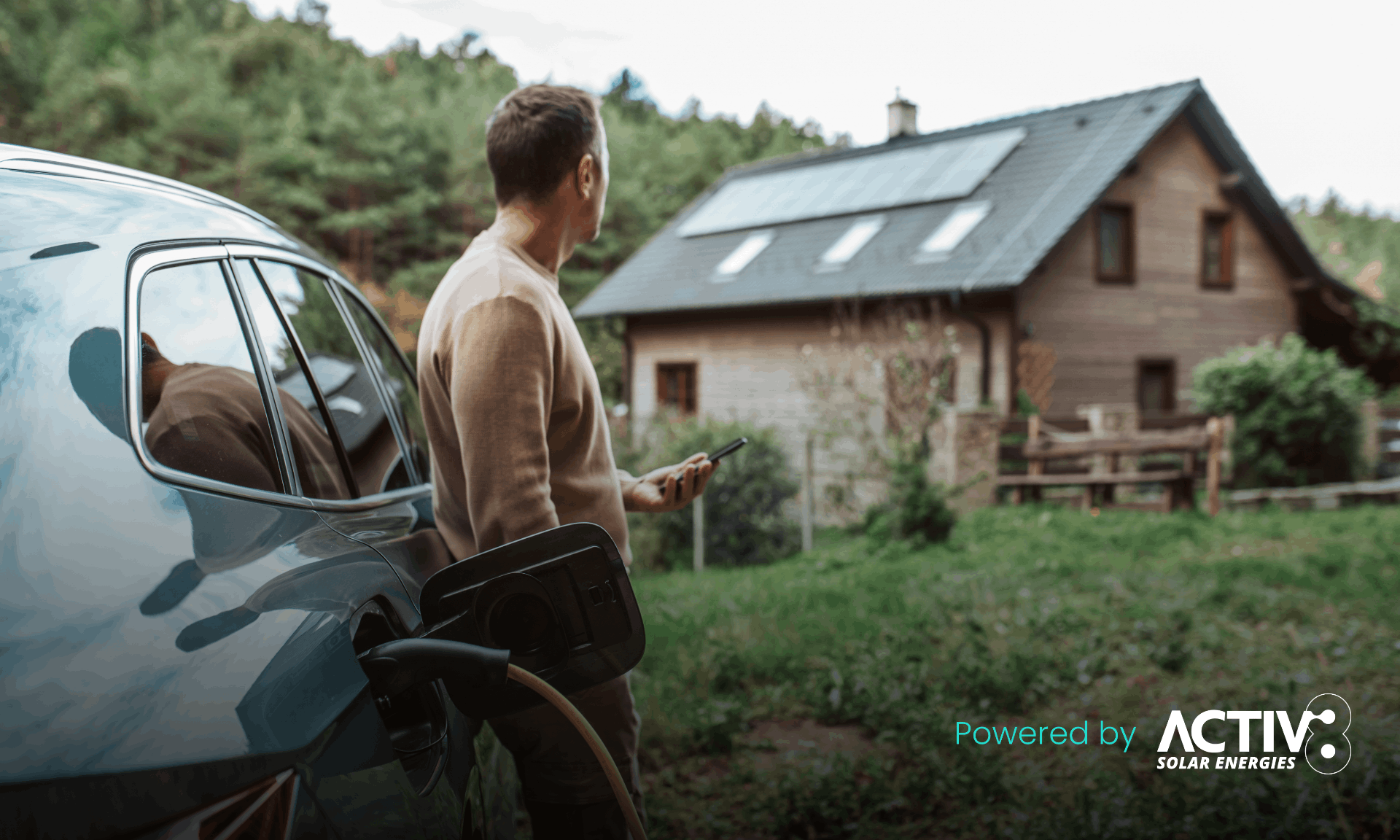 man charging car while on phone with house in background