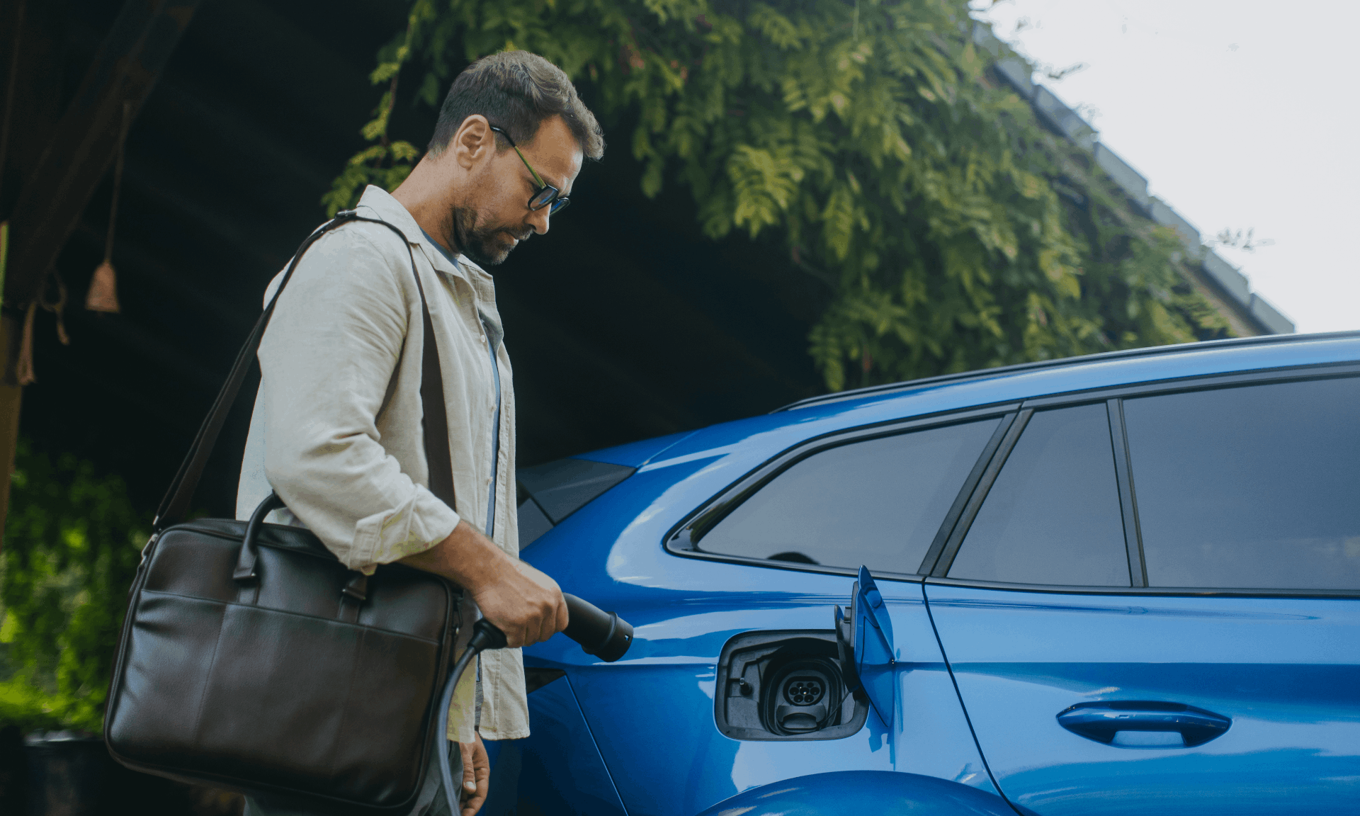 man plugging in blue electric car