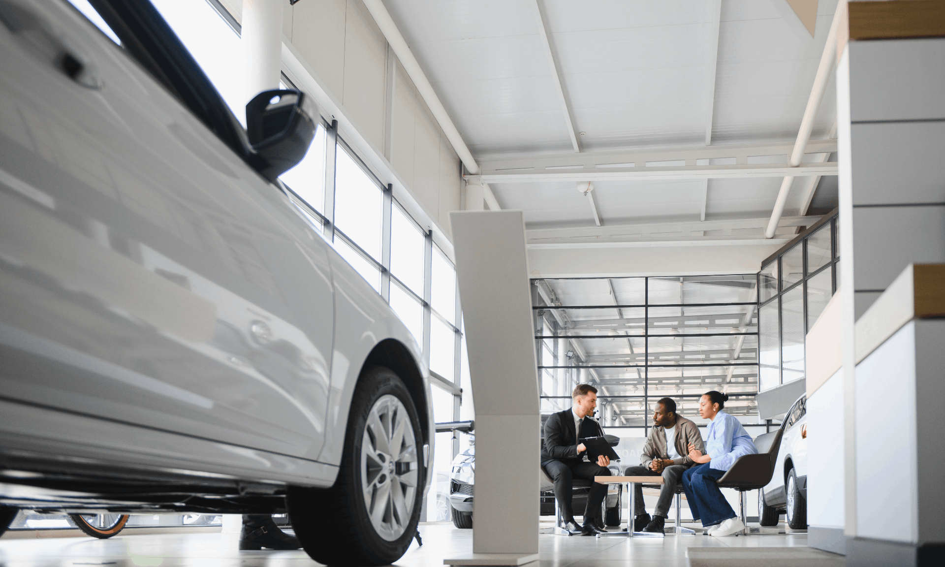 three people talking in a car delaership