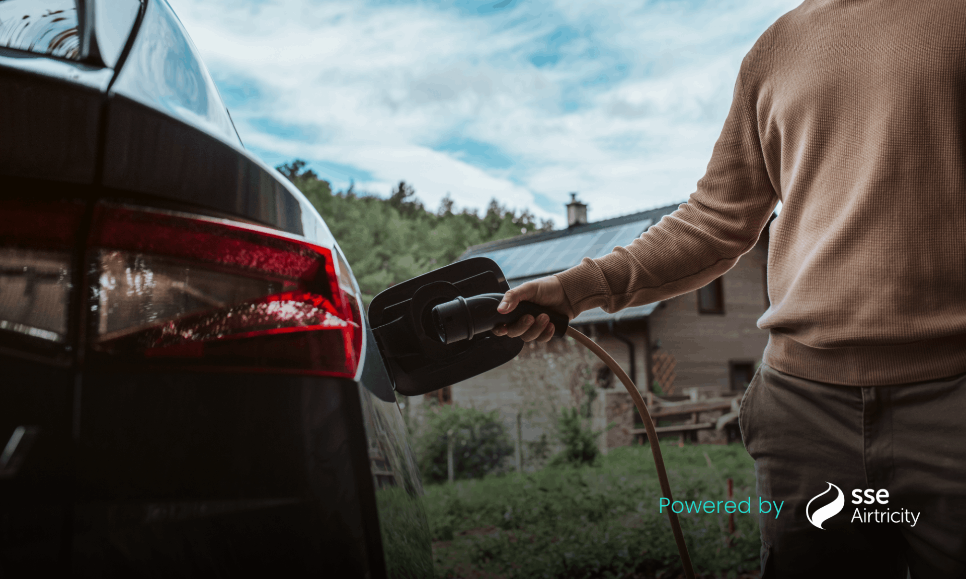 man in brown jumper charging car