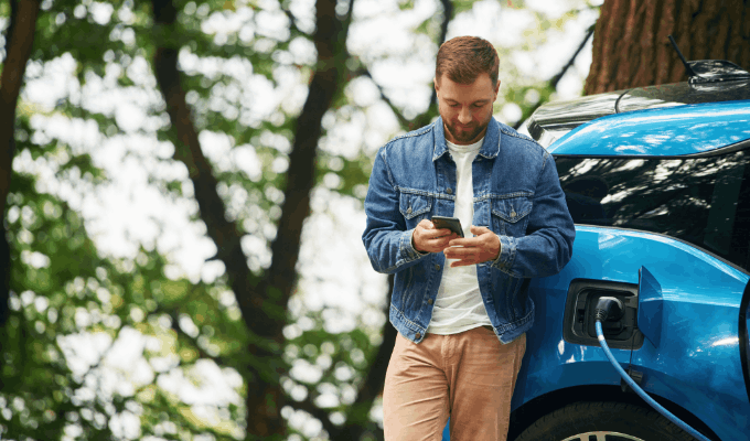 man in denim jacket charging blue car