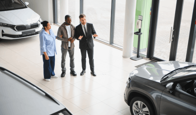 three people looking at a car in a garage