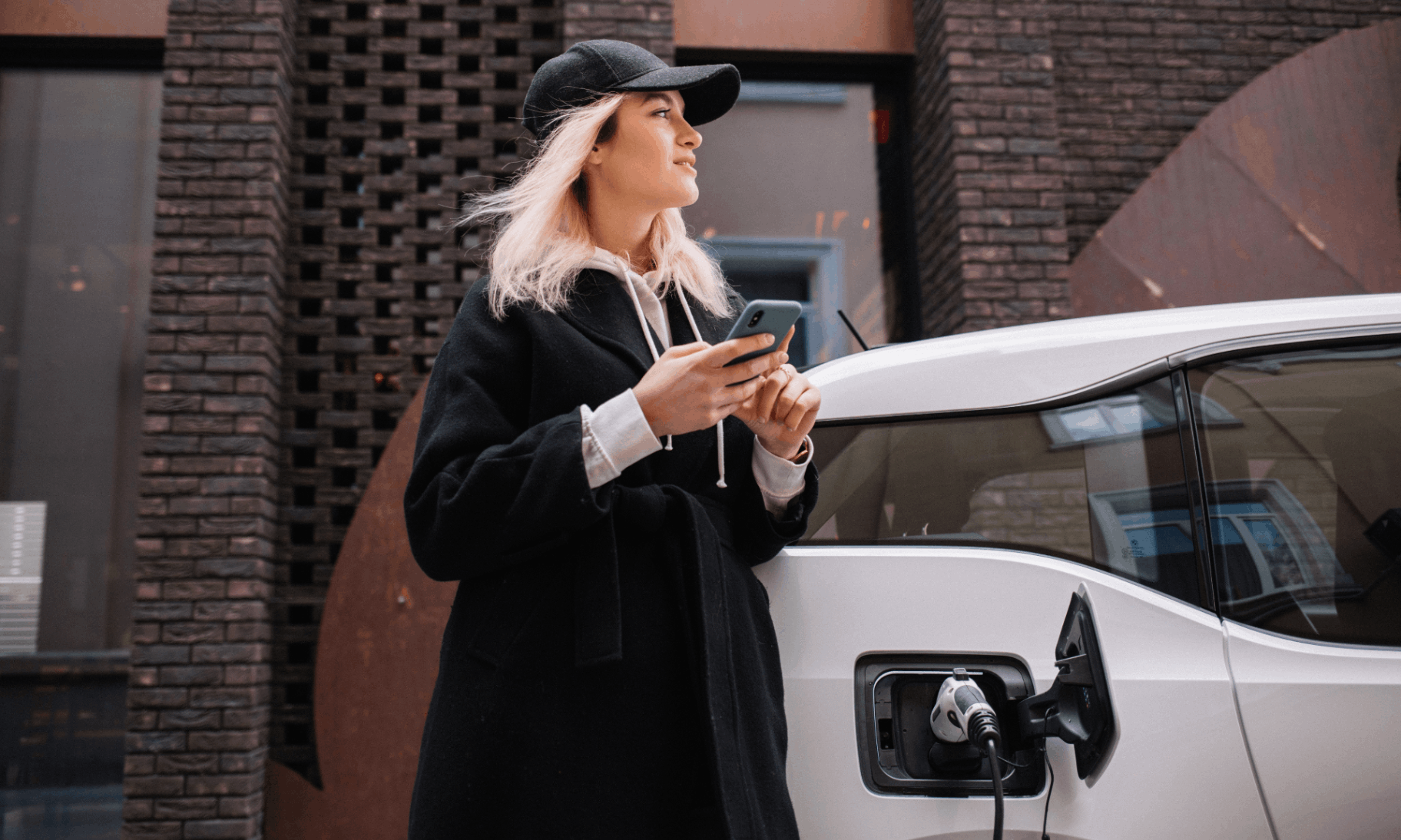 woman in cap charging white car